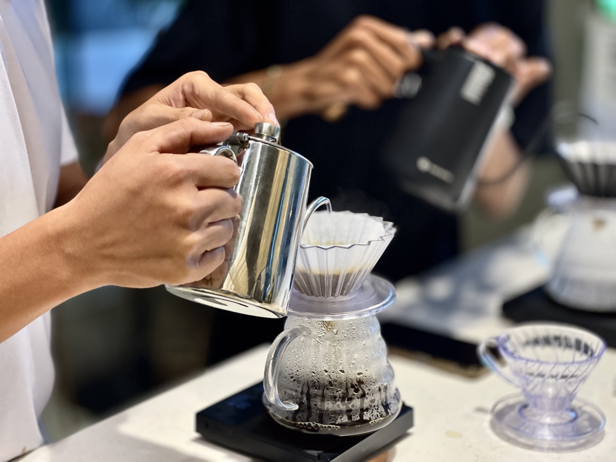 Barista hand-pouring a filter coffee through a dripper at Cafe 32nd St